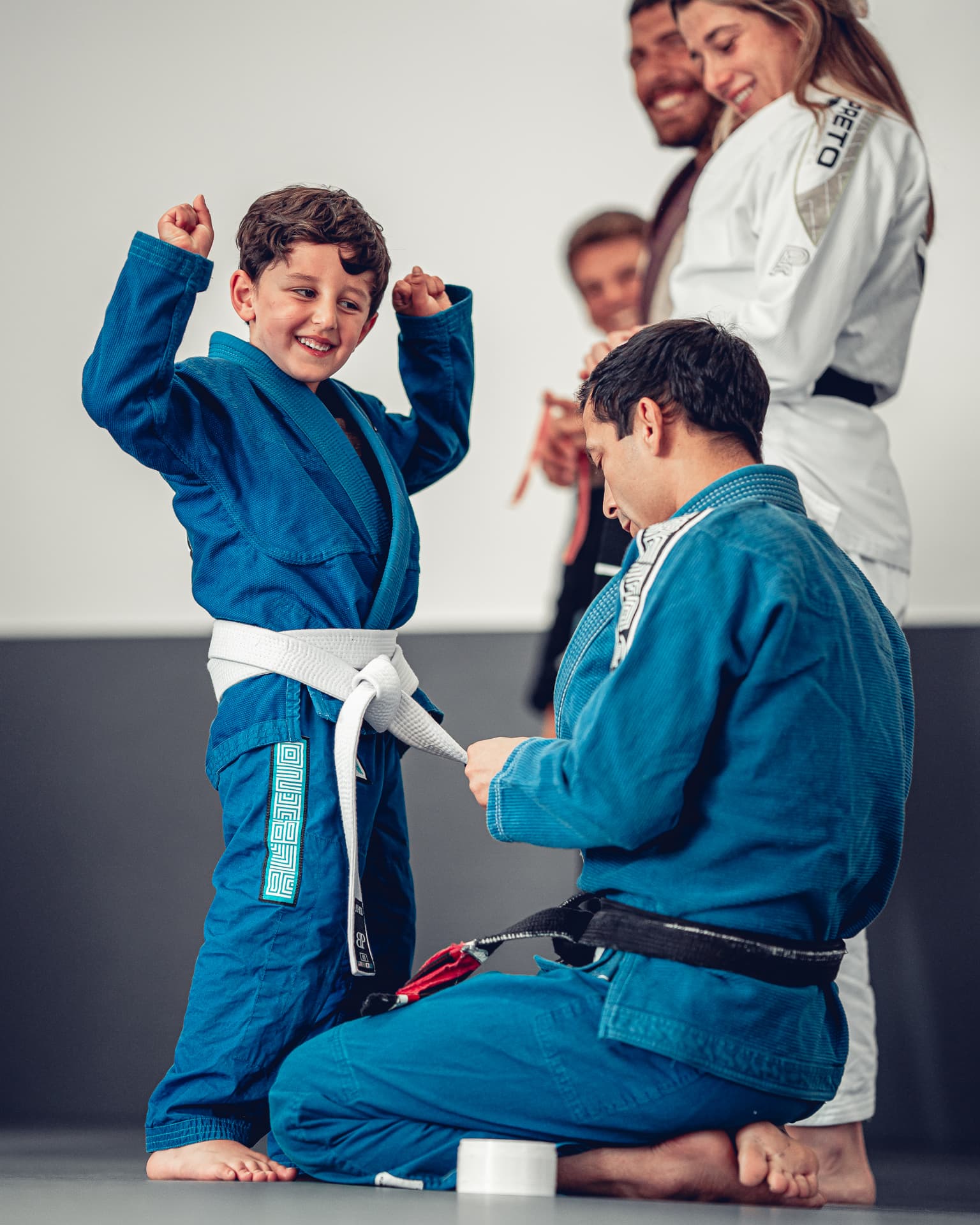 A young Del Mar Jiu-Jitsu Club student celebrating with his coach after earning a stripe.